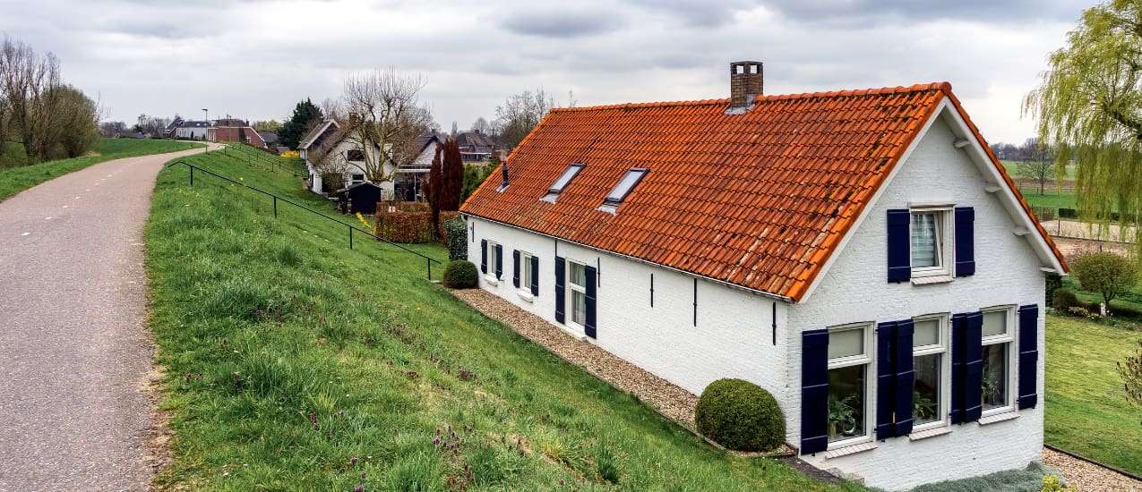 Hus der er hvidt med rødt tag ved siden af vej